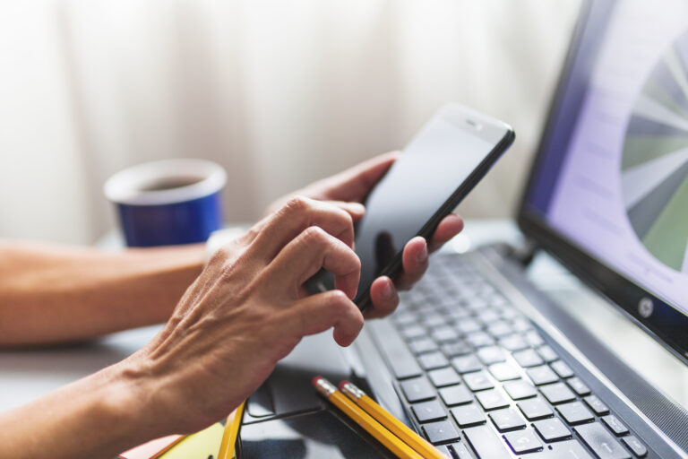 crop-hands-browsing-smartphone-office